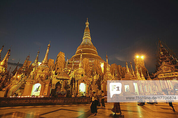 Besucher spazieren um die Shwedagon-Pagode bei Sonnenuntergang; Yangon  Burma