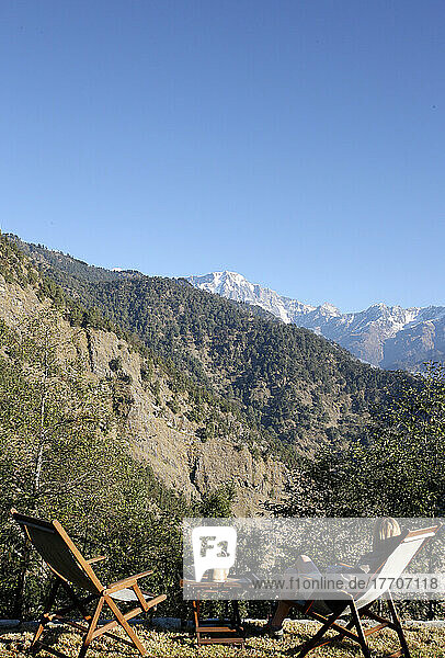 Ein Tourist sitzt mit Blick auf das indische Himalaya-Gebirge; Uttaranchal  Indien