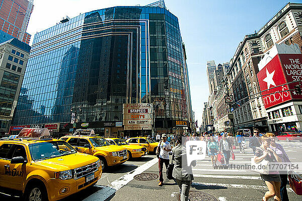 Reihe von Ny Taxis und Fußgängern beim Überqueren der Straße vor Macy's  dem größten Kaufhaus der Welt  Manhattan  New York  USA