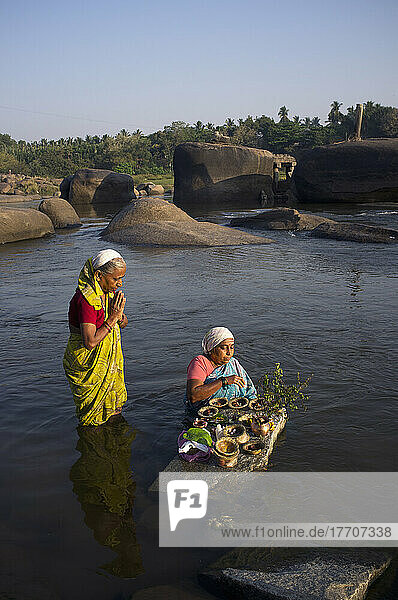 Frauen  die für eine religiöse Zeremonie im Fluss stehen; Hampi  Karnataka  Indien