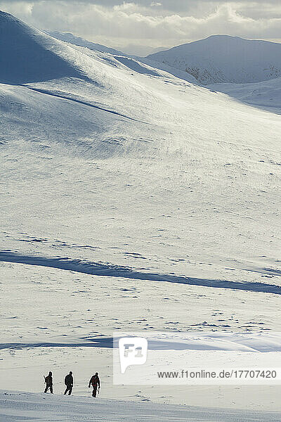 Drei Wanderer auf verschneiter Winterwanderung beim Abstieg vom Creag Pitridh in der Nähe von Laggan; Schottland