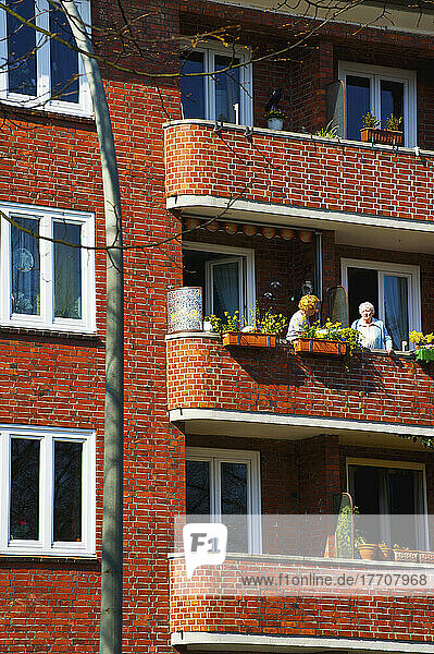 Freunde genießen den Balkon in einem Backsteinbau; Hamburg  Deutschland