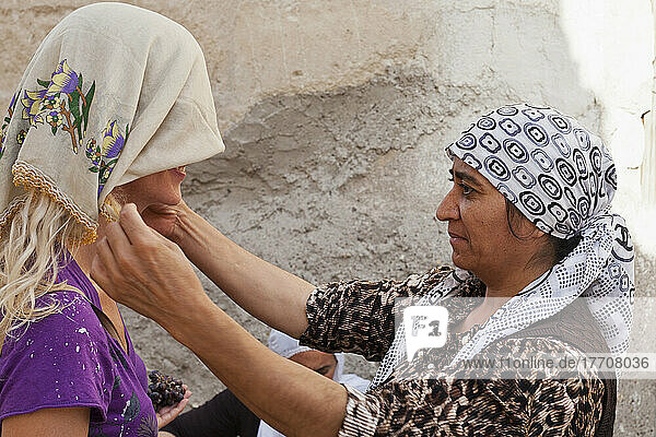 Eine Frau stattet eine Touristin mit einem Kopftuch aus; Goreme  Kappadokien  Türkei