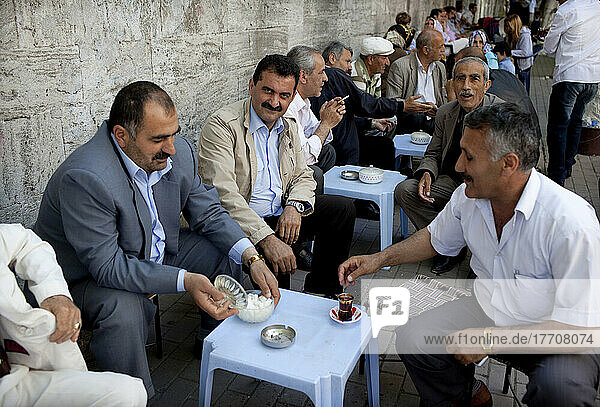 Men gather and drink tea around the walls of Fatih Mosque the boundary of the Carsamba Pazari  the Wednesday Market in Fatih. This is one of Istanbul's oldest and most colourful market places in Istanbul  Turkey.