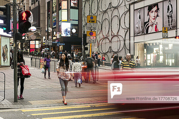 Unschärfe eines Fahrzeugs auf einer Straße  während ein Fußgänger auf die Überquerung wartet; Hongkong  China