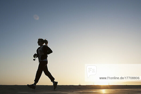 Silhouette einer Frau  die auf einem Pfad bei Sonnenaufgang spazieren geht; Kalifornien  Vereinigte Staaten von Amerika
