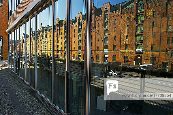 Ein braunes Backsteingebäude und eine Straße  die sich in den Fenstern eines Gebäudes spiegelt; Hamburg  Deutschland