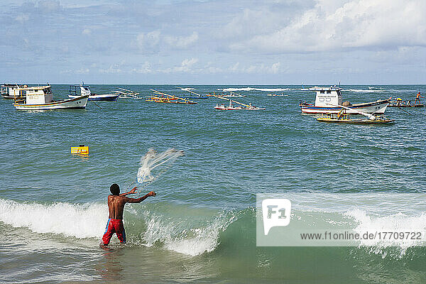 Ein Mann wirft ein Fischernetz vom Strand in Porto De Galinhas; Pernambuco  Brasilien