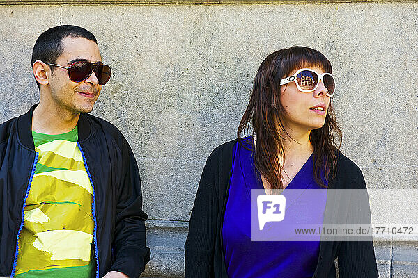 Ein Mann und eine Frau mit Sonnenbrille  die an einer Betonwand stehen; Barcelona  Spanien