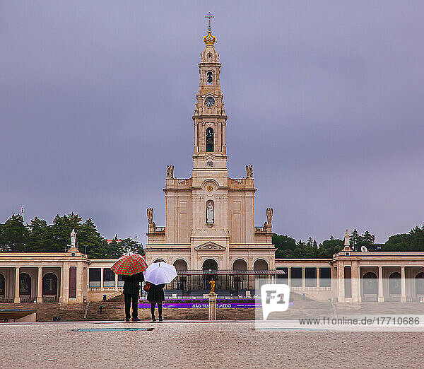 Touristen mit Regenschirmen stehen vor der Basilika Unserer Lieben Frau vom Rosenkranz  dem Heiligtum von Fatima; Fatima  Ourem  Portugal