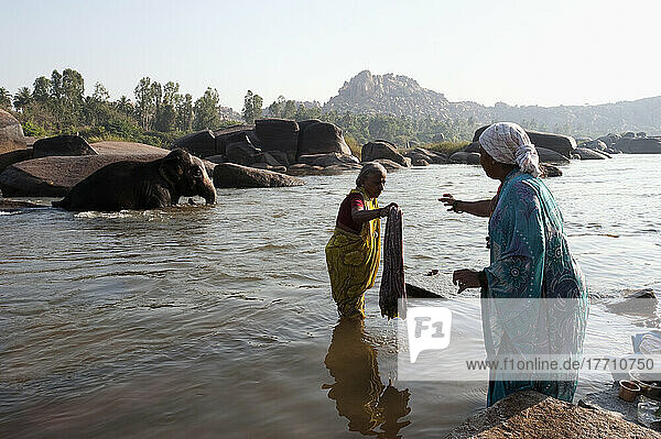Frauen waschen Kleidung im Fluss; Hampi  Karnataka  Indien
