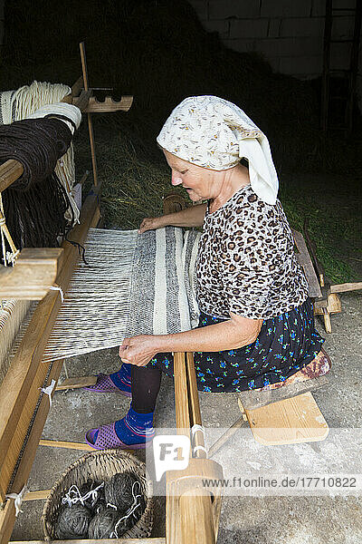 Traditionell gekleidete Frau beim Weben am Webstuhl in einem Dorf im Kreis Maramures; Siebenbürgen  Rumänien