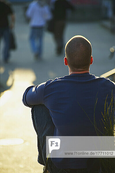 Ein Mann sitzt im Sonnenschein und beobachtet die Fußgänger; Hamburg  Deutschland