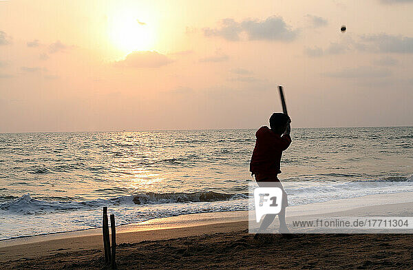 Playing cricket  the national sport of India  on Anjuna Beach at sunset  Goa State  India  Asia.