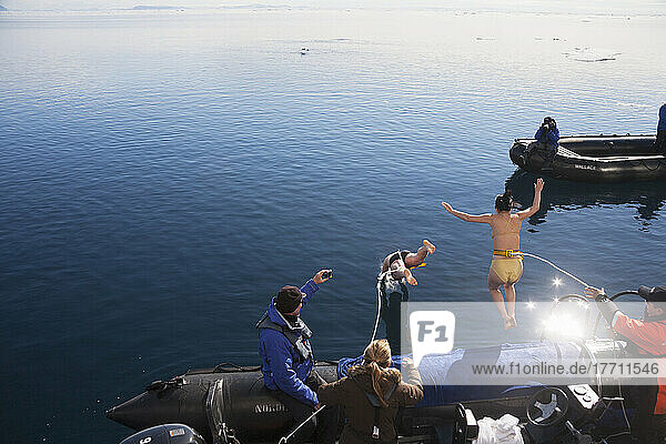 Touristen springen von einem Boot in das eiskalte Wasser des Arktischen Ozeans; Svalbard  Norwegen