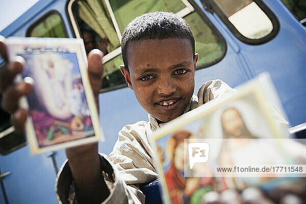 Junger Junge  der am Straßenrand religiöse Karten verkauft; Gondar  Äthiopien