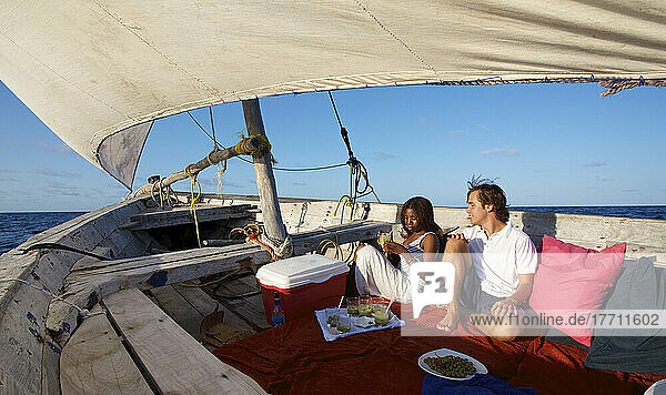 Ein Paar sitzt und genießt eine Mahlzeit auf einem Segelboot; Vamizi Island  Mosambik