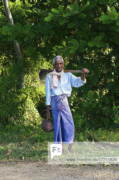 A Sri Lankan Man Standing At The Side Of A Road With A Shovel; Ulpotha  Embogama  Sri Lanka