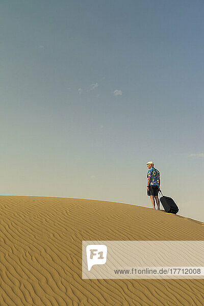 Barefoot Man With Suitcase On Sand Dune; Dubai  United Arab Emirates