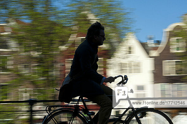 Silhouette Of Cyclist Going Past Canal And Gabled Houses; Amsterdam  Holland