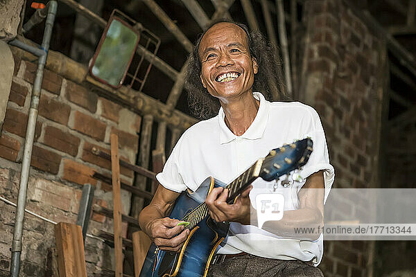 Eine Fahrradtour durch ein vietnamesisches Dorf in Hoi An. Ein einheimischer Mann spielt Gitarre für die Touristen; Hoi An  Quang Nam  Vietnam