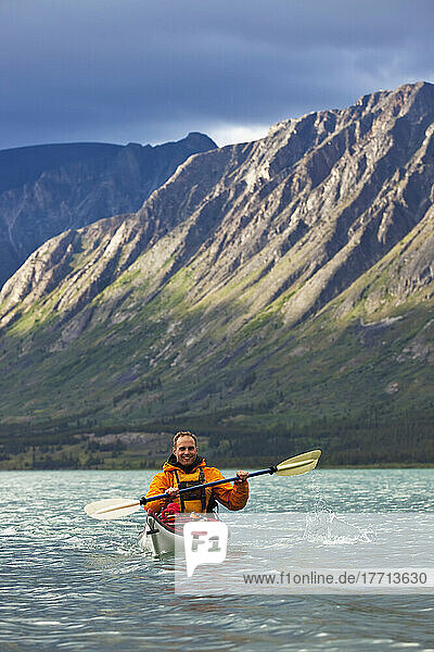 Kayaker On Kusawa Lake With The Setting Sun Hitting The Mountains; Yukon  Canada