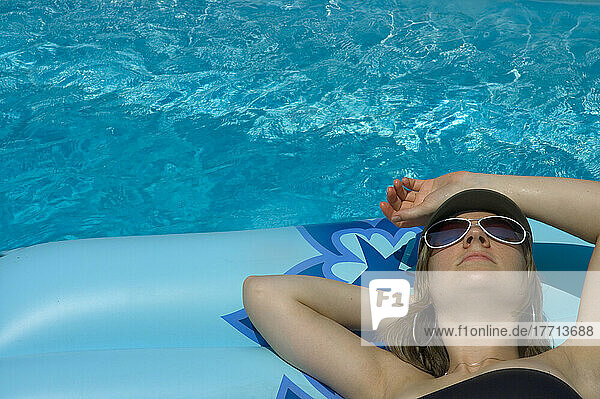 Frau auf Matratze im Pool liegend