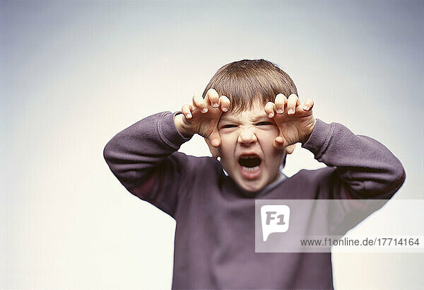 Fv0944  Matthew Plexman; Kleiner Junge  der mit den Händen neben seinem Gesicht in die Kamera brüllt und dabei unheimlich aussieht