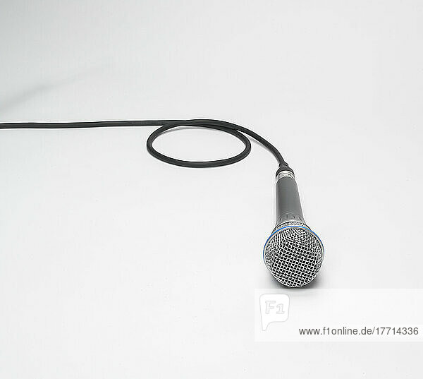 Handmikrofon mit Mikrofonkabel auf weißem Hintergrund; Studioaufnahme