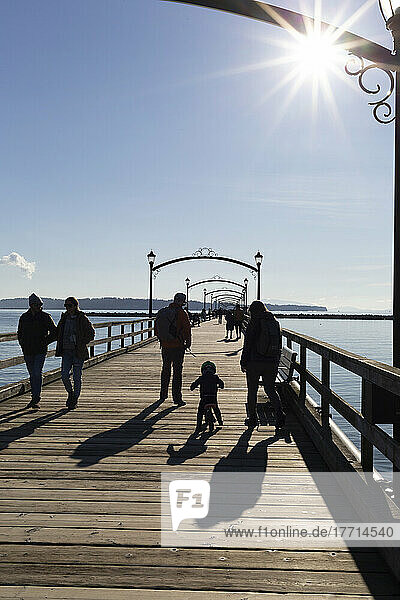 Families walk the pier in White Rock  BC on a sunny day; White Rock  British Columbia  Canada