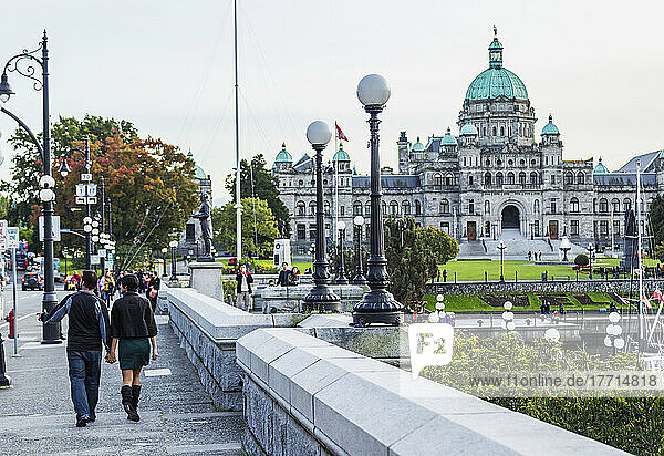 Ein junges Touristenpaar  das an der Uferpromenade in Richtung der Parlamentsgebäude spaziert; Victoria  Vancouver Island  British Columbia