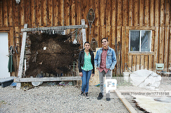 Native American Teenaged Boy And Girl Standing In Front Of A Stretched Buffalo Hide; Rossburn  Manitoba  Canada