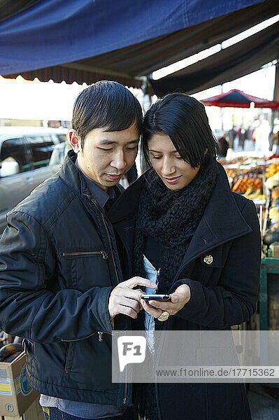 Young Couple Using A Cell Phone In Kensigton Market  Toronto  Ontario