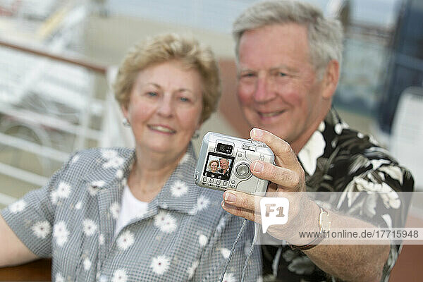 Senior Couple Taking Self Portrait Beside Deck Railing On Cruise Ship