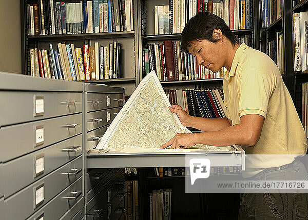 Mann in der Bibliothek  der die Karte betrachtet