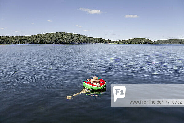 Woman Floating In A Watermelon Tube At The Lake  Algonquin Park  Ontario