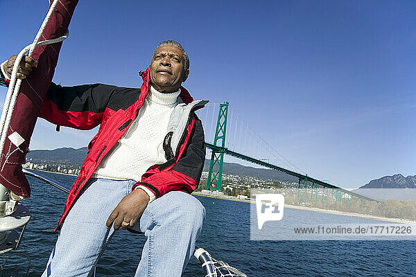 Senior Mann sitzt auf dem Bug seines Segelbootes  Vancouver Harbour  Bc