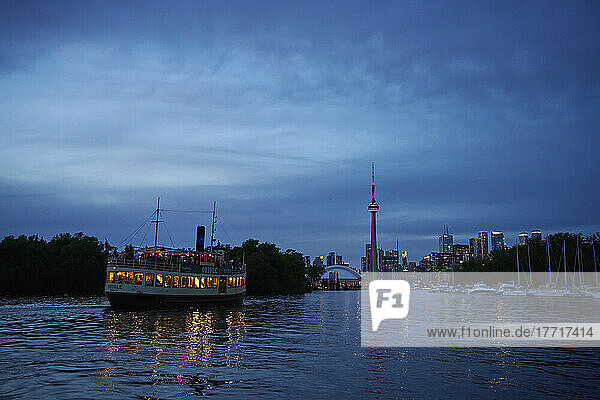 Summer cruise in the Toronto harbour at dusk with the skyline in the background; Toronto  Ontario  Canada