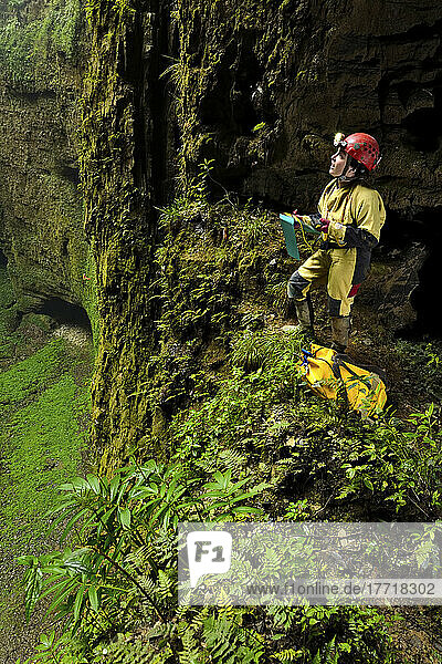 A speleologist on a small ledge overlooking the vast floor surface of Niubizi Tian Keng in the Er Wang Dong cave system.