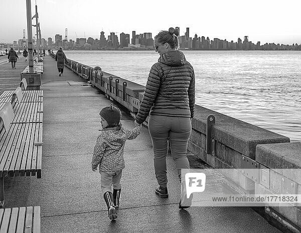 Mother and young daughter hold hands and walk at Lonsdale Quay; North Vancouver  British Columbia  Canada
