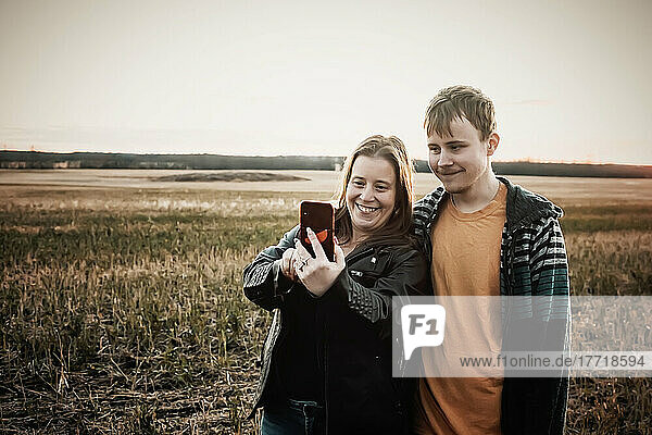 A mother with epilepsy taking a self-portrait with her son who has Aspberger Syndrome in a field on a farm after harvest; Westlock  Alberta  Canada