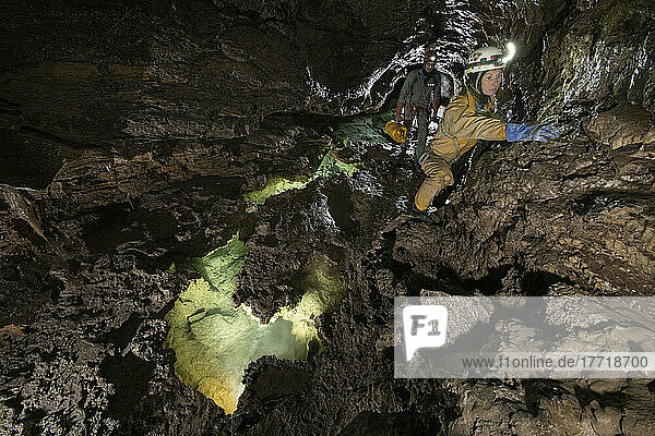 Zwei Forscher klettern an einem kleinen Quergang oberhalb einer Reihe kleiner Wasserbecken in der Veryovkina-Höhle. Während des Hochwasserimpulses  der eine Woche nach der Aufnahme dieses Fotos durch die Höhle floss  füllte sich alles bis zum Dach mit Wasser; Gagra  Kaukasus  Abchasien