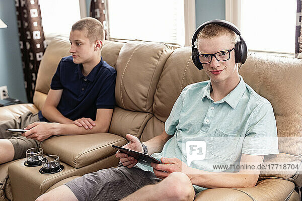 Junge erwachsene Brüder nutzen Tablet und Smartphone gemeinsam zu Hause; Edmonton  Alberta  Kanada
