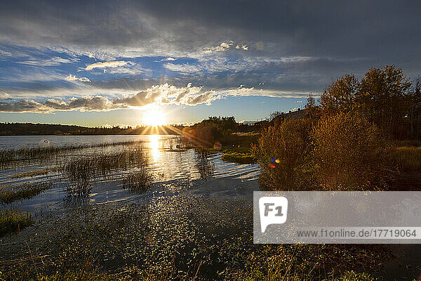 Sunburst der untergehenden Sonne über einem See im Herbst; 108 Mile House  British Columbia  Kanada
