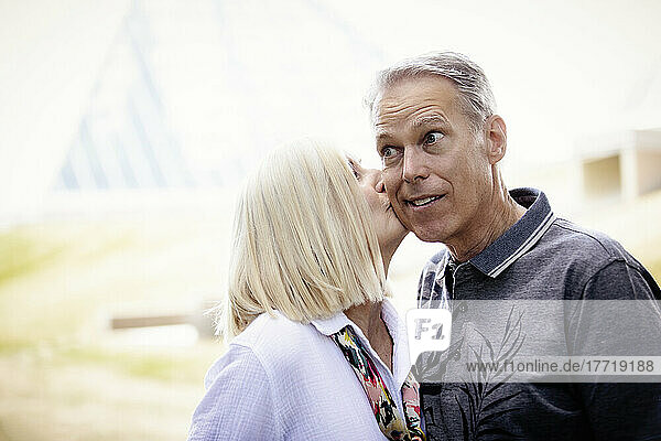 Ehefrau küsst die Wange ihres Mannes  der einen überraschten Gesichtsausdruck hat; Edmonton  Alberta  Kanada