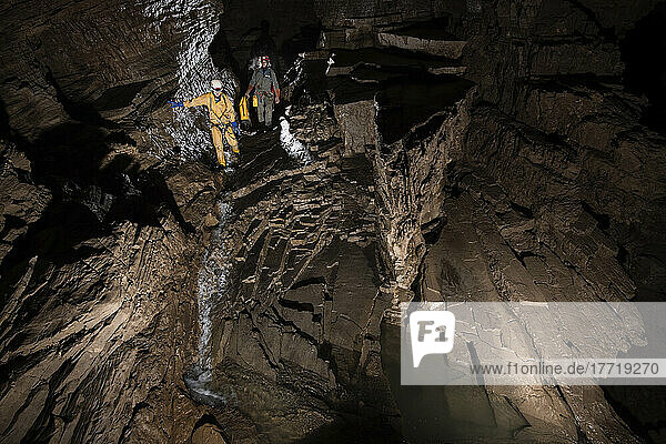 Zwei Forscher gehen einen stufenförmigen Gang entlang eines kleinen Baches in der Veryovkina-Höhle hinunter. Die Felsformationen in diesem Teil der Höhle sind wunderschön und wirklich ungewöhnlich. Während des Hochwasserimpulses  der eine Woche nach der Aufnahme dieses Fotos durch die Höhle floss  füllte sich alles bis zur Decke mit Wasser; Gagra  Kaukasusgebirge  Abchasien