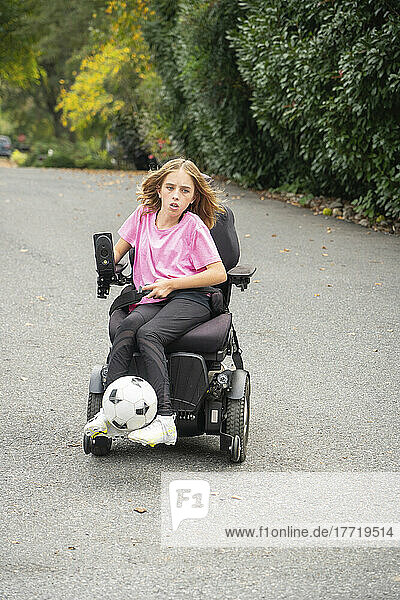 Eleven year old girl with Ullrich Congenital Muscular Dystrophy plays soccer in her wheelchair near her home; Cabin John  Maryland  United States of America