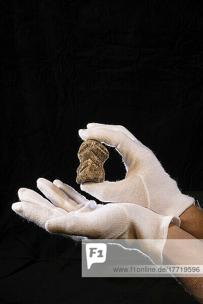 Dies ist ein Foto der behandschuhten Hände eines Wissenschaftlers  der den Knochen eines Riesenhirsches oder Megaloceros mit der eingravierten Neandertaler-Gravur hält. Der Knochen wurde erstmals von einem Doktoranden der Universität Tübingen  Deutschland  gefunden. Er wurde in der Sedimentfüllung der Ausgrabungsstätte in der Nähe der Einhornhöhle bei Scharzfeld im Harz gefunden. Der Knochen ist etwa 6 cm groß; Studio