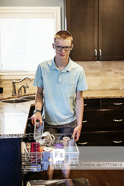 Junger Mann räumt den Geschirrspüler zu Hause aus; Edmonton  Alberta  Kanada