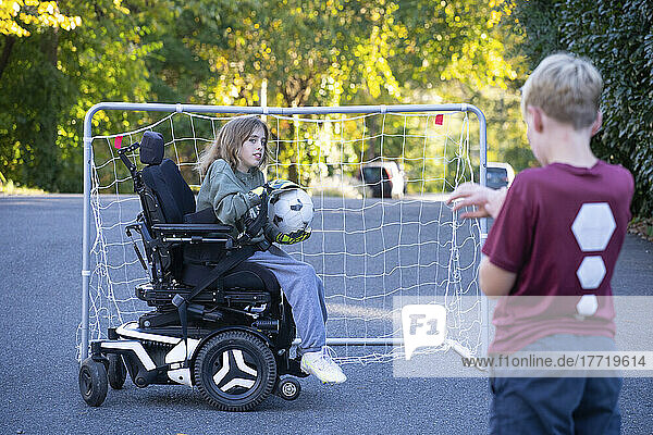 Eleven year old girl with Ullrich Congenital Muscular Dystrophy plays soccer in her wheelchair with a friend near her home; Cabin John  Maryland  United States of America